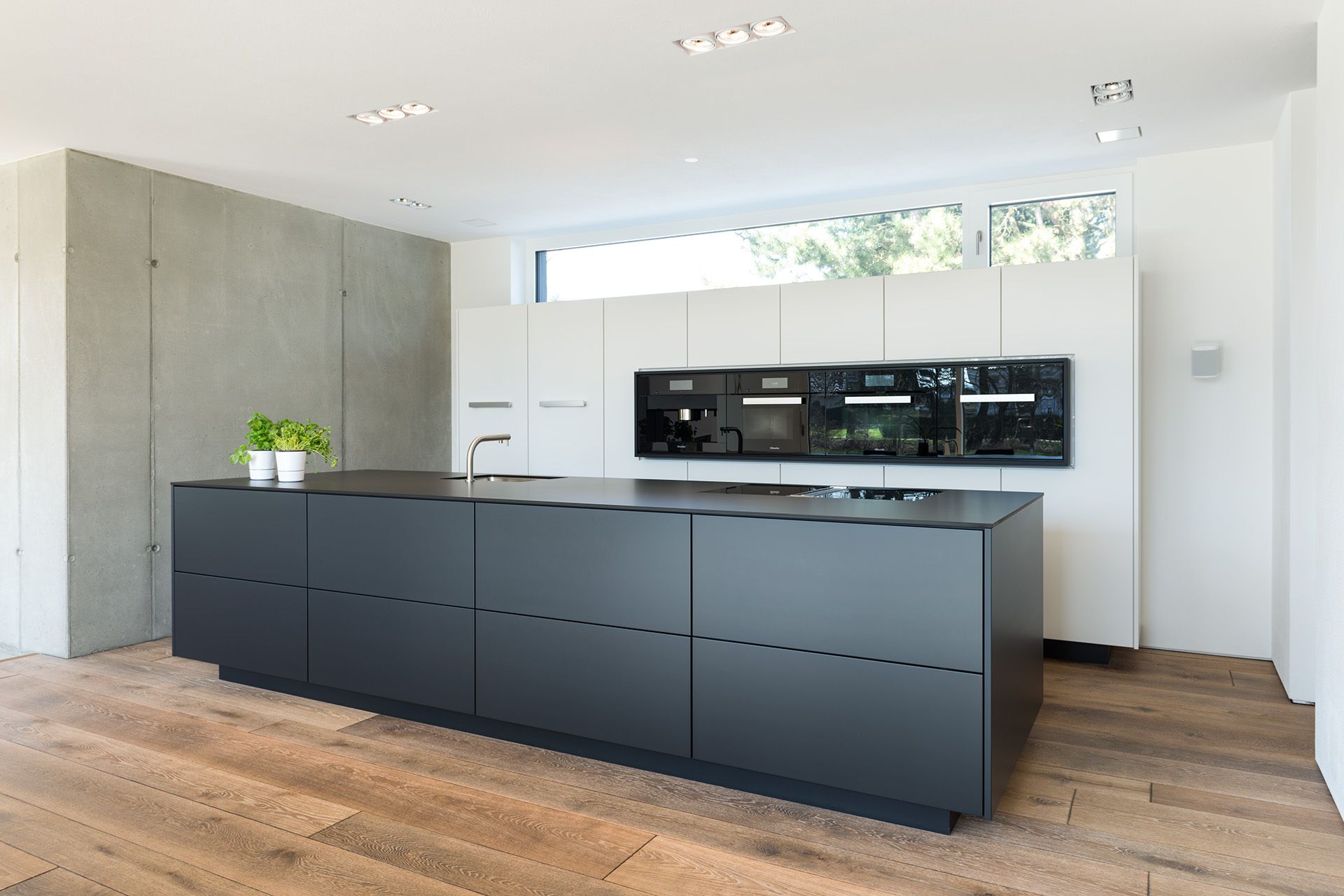 Kundenküche Schwarz-Weiß: Minimalistisches Design mit Holzboden, Kochinsel und hochwertiger Ausstattung